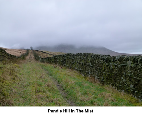 Walking down a broad track with Pendle Hill disappearing into the mist/low cloud.