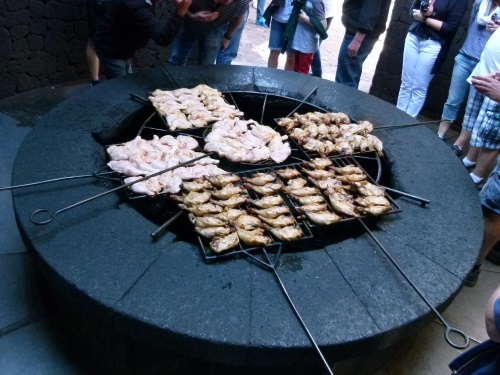 Chickens roasting over fire pit.