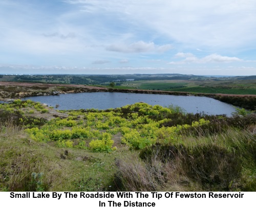 Small lake by the roadside. The tip of Fewston Reservoir is just visible.