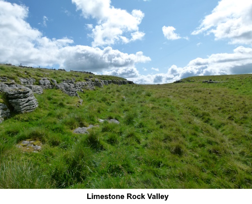 A shallow valley flanked by limestone outcrops.